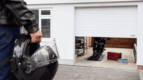 Motorcyclist opening Garolla electric garage door to access motorcycle
